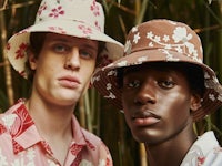 two men in floral hats standing next to bamboo